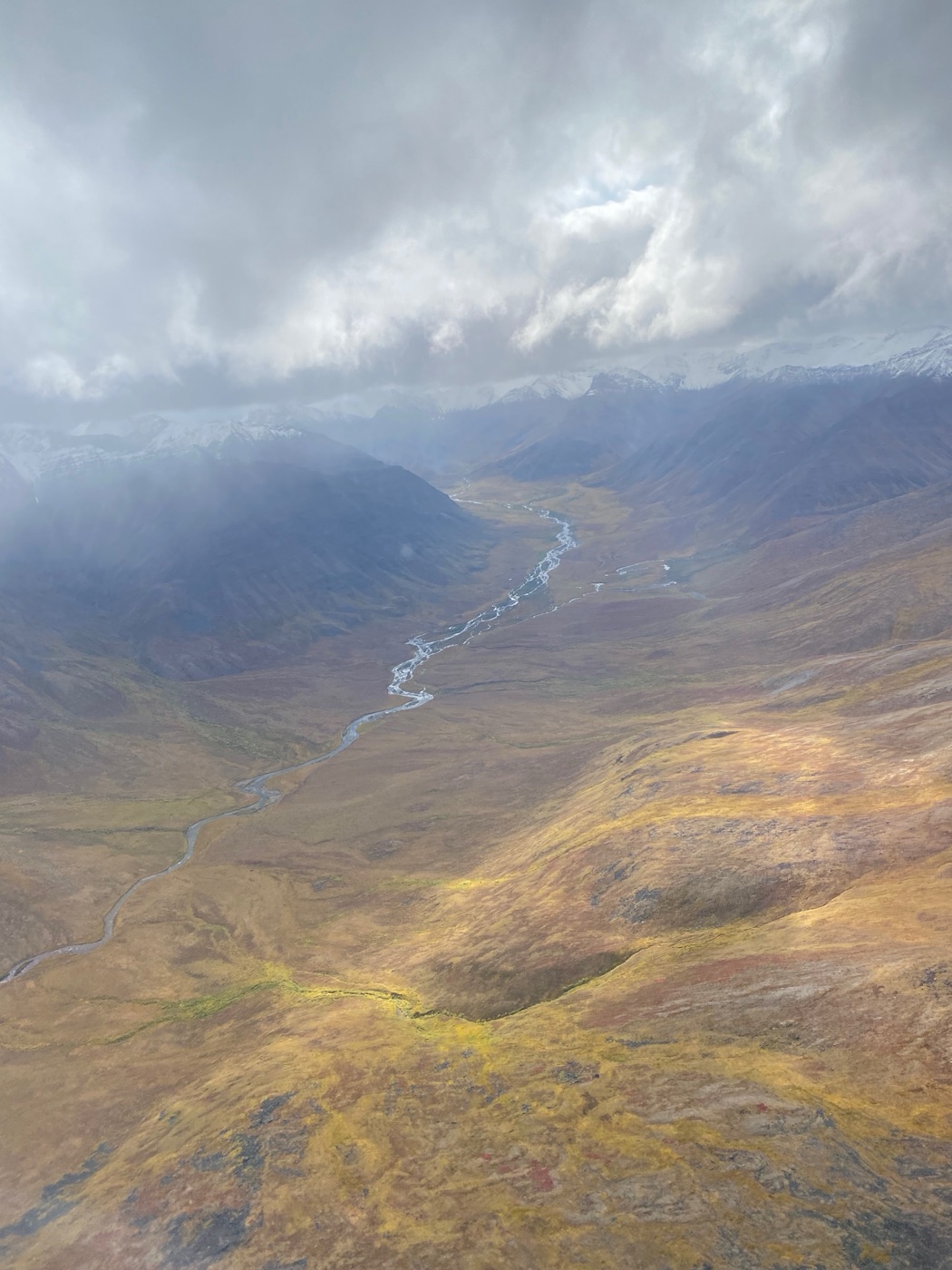 A remote river valley winding through the Brooks Range under low clouds in Gates of the Arctic National Park.