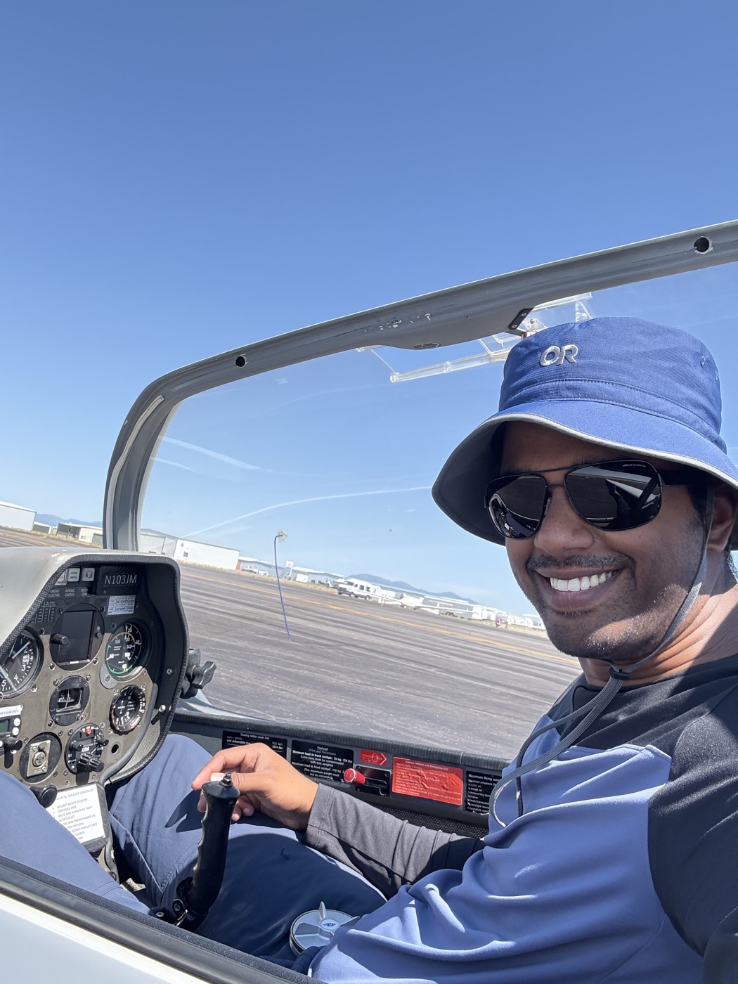 Arvind seated at the controls in a glider cockpit.