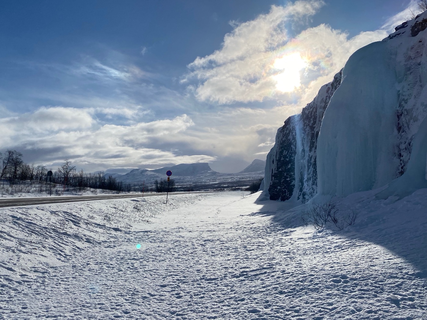 A frozen waterfall and snowy mountain landscape above the Arctic Circle in Sweden.
